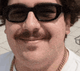 a man with a mustache wearing sunglasses and a gold chain