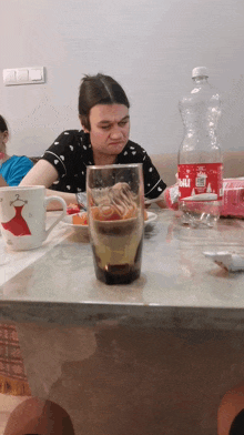 a woman is sitting at a table with a bottle of bali on it