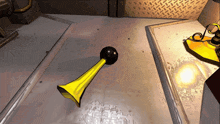 a yellow horn with a black handle is on a concrete floor