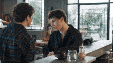 two young men are sitting at a counter in a restaurant talking