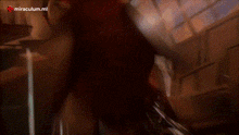 a person is holding a sword in a dark room with a brick wall in the background .
