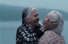 two older women are hugging each other and smiling .