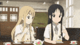 two anime girls are sitting at a table with a box of truf tea