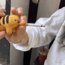 a person is holding a toy tiger and a cigarette