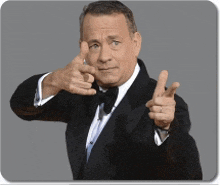 a man wearing a tuxedo and bow tie is pointing at the camera