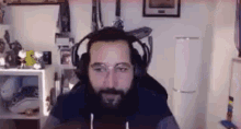 a man with a beard is wearing headphones and glasses while sitting in a chair in a room .