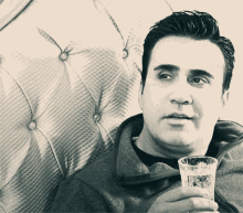 a man is sitting on a couch holding a glass
