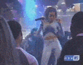 a woman is singing into a microphone in front of a crowd and a sign that says ' tp ' on it