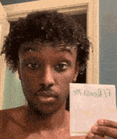 a man with curly hair is holding up a piece of paper that says ' sm f00a17 ' on it