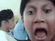a man is making a funny face with his mouth open and a girl is behind him .