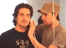 two men are talking on a phone and one has a shirt that says oberh on it