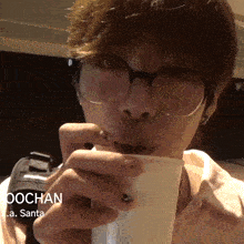 a man wearing glasses is drinking from a cup with the name jochan written on it