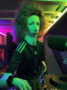 a person wearing an adidas shirt is playing a dj mixer