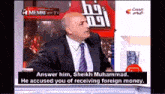 a man in a suit and tie is speaking on a television show
