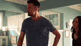 a man and a woman are standing in a living room with their hands on their hips .