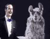 a man in a tuxedo and bow tie stands next to a white furry animal