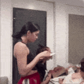 a woman in a black tank top is standing next to a woman in red shorts