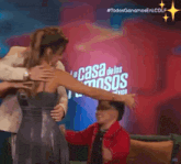 a group of people hugging in front of a sign that says la casa de los famosos mexico