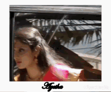 a woman is sitting in a car with her hair blowing in the wind .