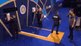 a group of men are standing around a dart board in a room .