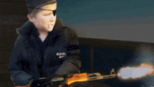 a young boy wearing an eye patch and a buick jacket holds a gun