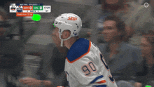 a hockey player with the number 90 on his jersey stands in front of a scoreboard