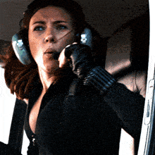 a woman wearing headphones and a glove is sitting in a car