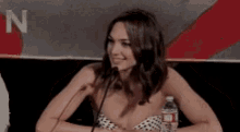 a woman is sitting at a table with a microphone and a water bottle .