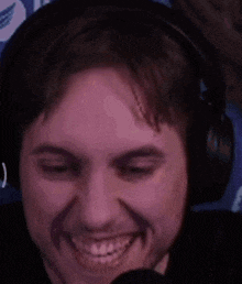 a man wearing headphones and a microphone is smiling .