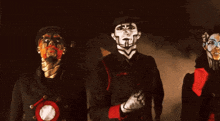 a group of people with face paint on their faces are standing in a dark room