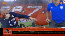 a man in a blue shirt is sitting in front of a ninja tv screen