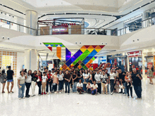 a group of people posing for a picture in a shopping mall with a world balance store in the background