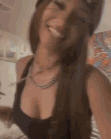 a woman wearing a hat and a black tank top is smiling and looking at the camera .