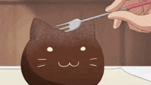 a person is holding a fork over a chocolate cat cake .