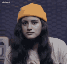 a woman wearing a yellow beanie and a white t-shirt