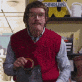 a man in a red vest is holding a purse