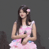 a woman in a pink and white dress holds a microphone