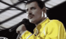 a man in a yellow jacket is holding a microphone .