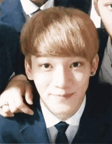 a young man in a suit and tie is smiling and looking at the camera