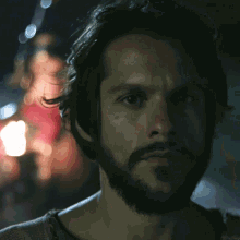 a man with a beard is looking at the camera with a blurry background