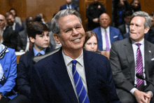 a man in a suit and tie is smiling in front of a crowd of people