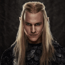 a man with long blonde hair and ears is wearing a black outfit