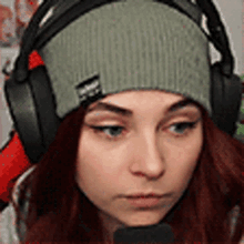 a woman wearing a beanie and headphones is looking at the camera .
