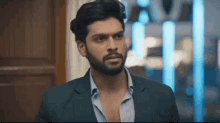 a man with a beard wearing a suit and a blue shirt