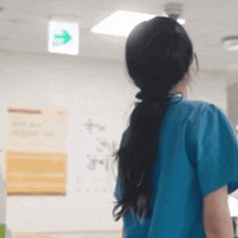 a woman in a blue scrub is standing in front of a green exit sign .