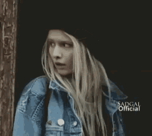 a woman with long blonde hair wearing a black hat and a denim jacket says badgal official on the bottom