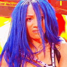 a woman with blue hair is crying and looking at the camera