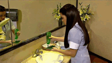 a woman is washing her hands in a bathroom sink with a bottle of soap on the counter
