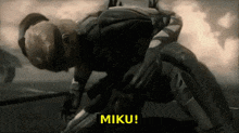 a video game character is laying on the ground with the words miku written above him .