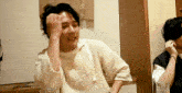 a man in a white sweater is making a funny face with his hand